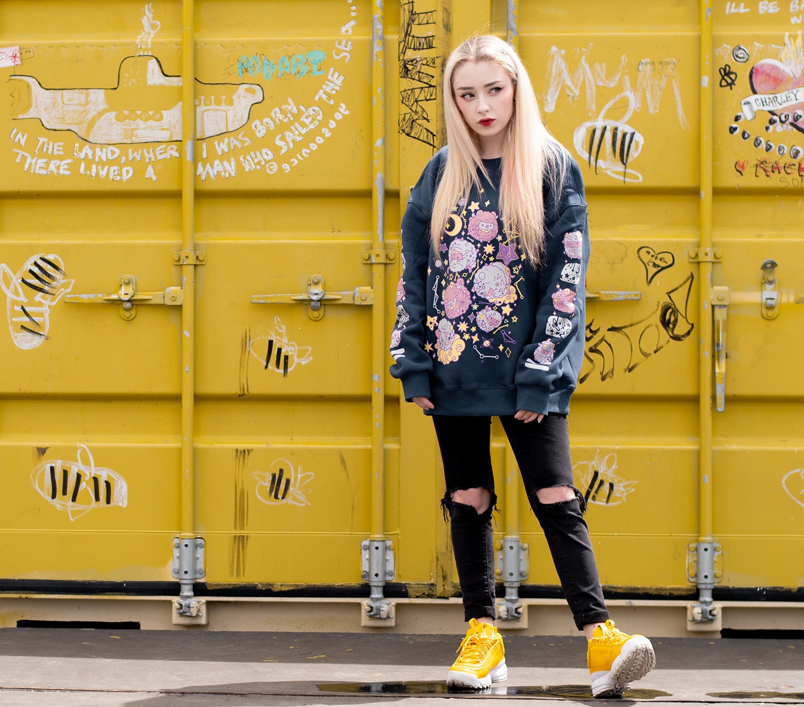 This thick navy colored sweatshirt features a front design of floating sheep in space, surrounded by starry skies and planets. The sweater is made of thick jersey fabric with a soft warm fleece interior. On both sleeves there is a column of floating sheep and starry sky elements that run down the entire sleeve. The sweatshirt comes in sizes XS to 2XL.