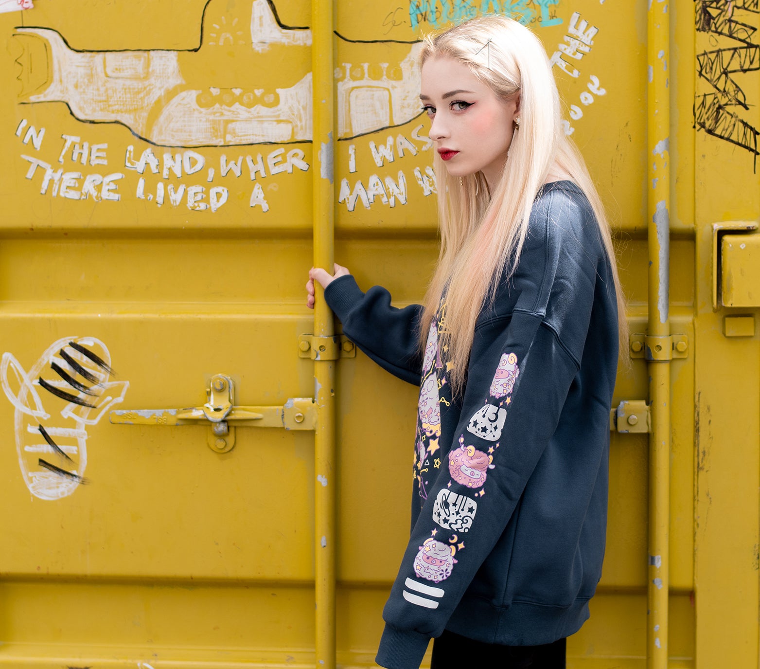This thick navy colored sweatshirt features a front design of floating sheep in space, surrounded by starry skies and planets. The sweater is made of thick jersey fabric with a soft warm fleece interior. On both sleeves there is a column of floating sheep and starry sky elements that run down the entire sleeve. The sweatshirt comes in sizes XS to 2XL.