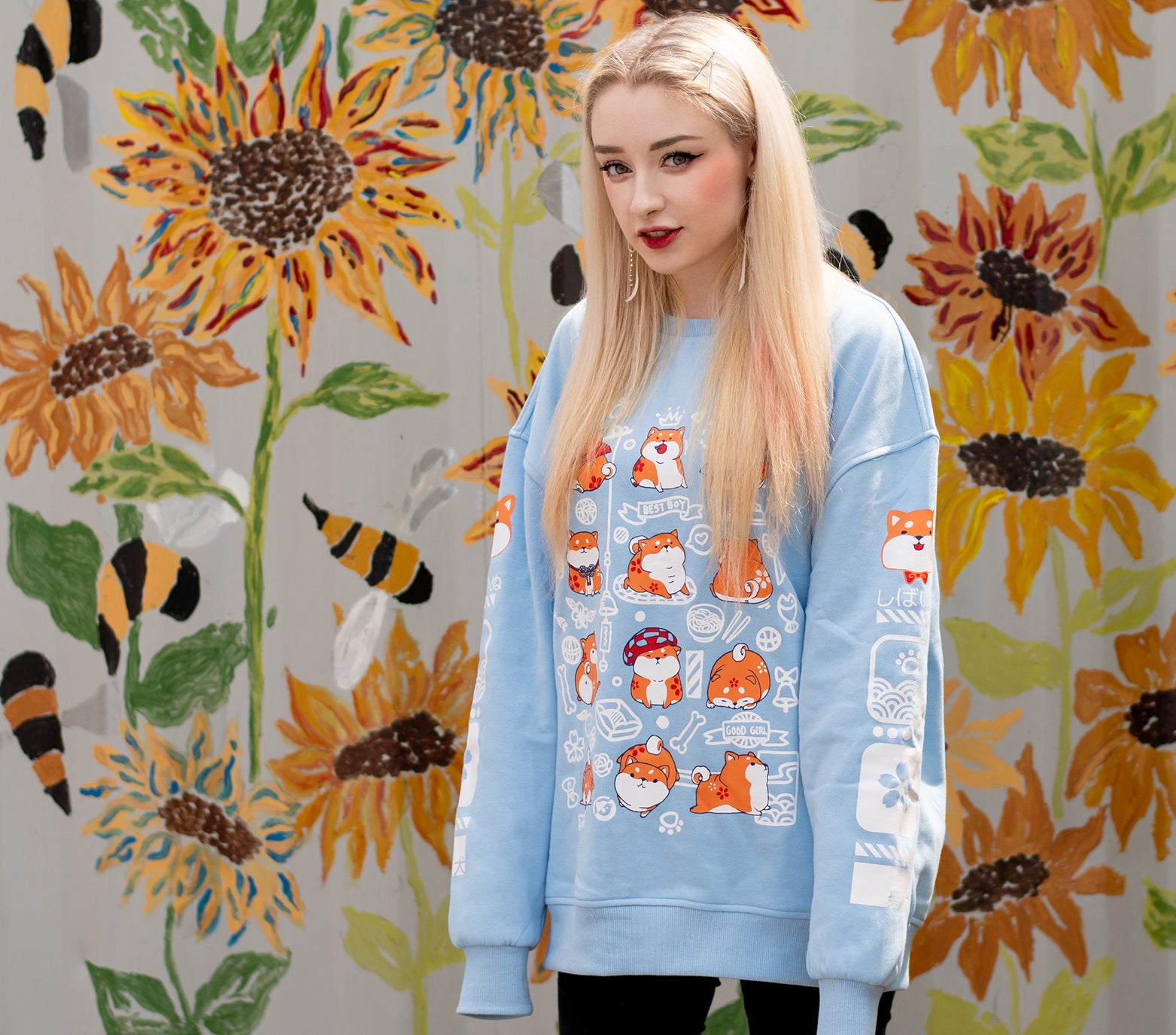 This light blue sweatshirt features a front design of a group of shiba inu in various adorable poses. The design captures the various antics of the shiba inu. Both sleeves also feature designs that run down the sleeves, which matches the front main design of the sweatshirt. The material is medium heavy jersey style with a soft fleece interior. The sweatshirt comes in sizes from XXS to 2XL. 